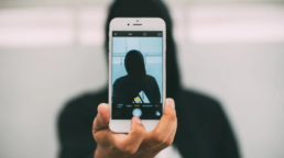 Ein Mann in einem schwarten Kaputen-Pullover, der ein Selfie von sich macht