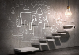 Eine leuchtende Glühbirne vor Wand mit technischen Zeichnungen